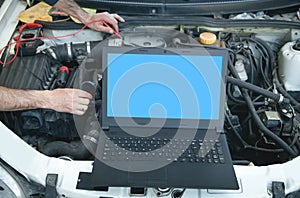 Mechanic with a multimeter testing car engine. Laptop on car engine. Car service. Diagnostic car engine