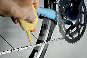 Mechanic oiling bicycle chain and gear with oil