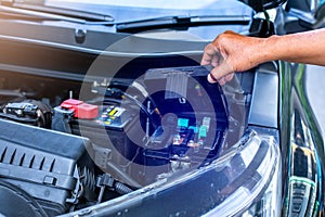 A mechanic is opening the cover of a car's electrical system control box