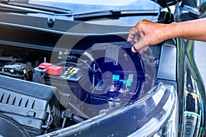 A mechanic is opening the cover of a car's electrical system control box