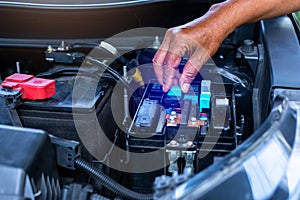 A mechanic is opening the cover of a car's electrical system control box