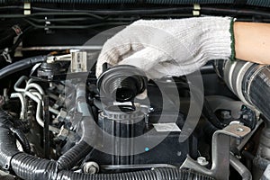 A mechanic is opening the oil cap from a car engine.