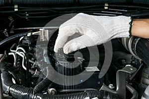 A mechanic is opening the oil cap from a car engine.