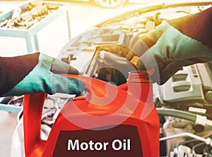 Mechanic opens the cap of a red colored gallon of motor oil