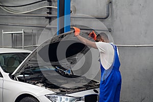 Mechanic in overalls inspects the car engine