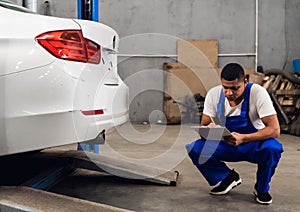 A mechanic in overalls inspects a car in a workshop