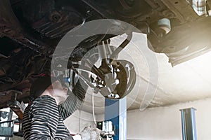 A mechanic performing diagnostics and repairs of a car, the front and background background is blurred with bokeh effect