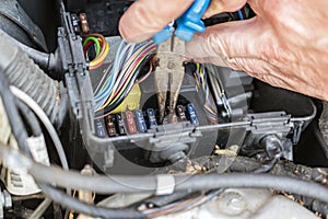 Mechanic with pliers checking the car fuse box of car photo