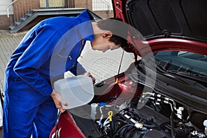 Mechanic pouring antifreeze into windscreen water tank photo