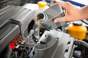 Mechanic pouring oil into car engine photo