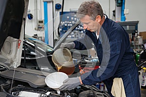 Mechanic Pouring Oil In Car Engine