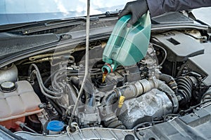 mechanic pouring oil to car engine. auto motor service