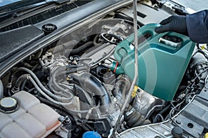 Mechanic pouring oil to car engine. auto motor service