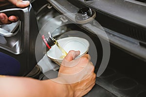 mechanic pouring oil to vehicle engine. serviceman changing motor oil in automobile repair service. maintenance & checkup in car