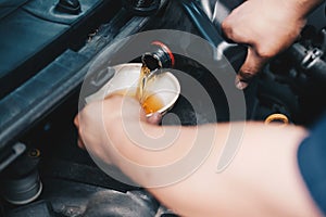 Mechanic pouring oil to vehicle engine. serviceman changing motor oil in automobile repair service. maintenance & checkup in car