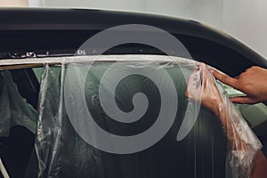 Mechanic preparing a car for painting by protecting the edges.