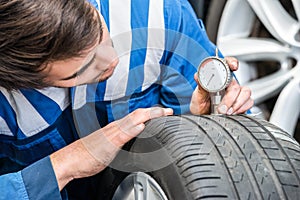 Mechanic Pressing Gauge Into Tire In Garage