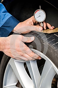 Mechanic Pressing Gauge Into Tire In Garage