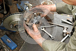 Mechanic pushing new brake pad into old caliper.