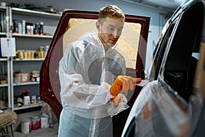 Mechanic puttying plastering car body in garage photo