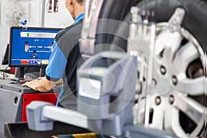 A mechanic reading the computer used to assess the wheel alignment process