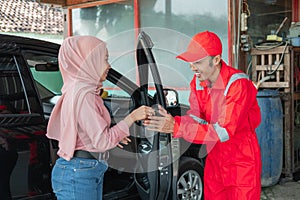 The mechanic in red receives the car keys when the customer comes by car to be repaired
