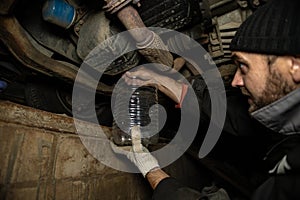 The mechanic removes the plug from the tank, draining the old engine oil from the engine. A mechanic holds a container