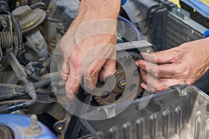 the mechanic removes the timing belt,a man removes a car belt from the engine with his hands, replacing a timing belt, car repair