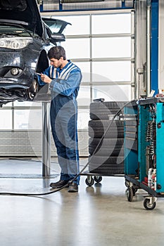 Mechanic Repairing Brake Of Lifted Automobile At Garage