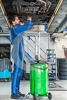 Mechanic Repairing Car On Hydraulic Lift In Automobile Shop