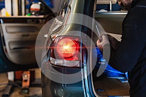 Mechanic repairing car rear light. Electromechanical workshop. Working with his hands. Tools. Concept of car repair