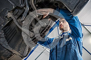 Mechanic Repairing Suspension System Of Car In Garage