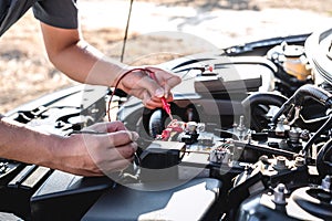 Mechanic repairman checking engine automotive in auto repair service and using digital multimeter testing battery to measure