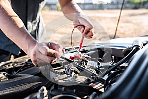 Mechanic repairman checking engine automotive in auto repair service and using digital multimeter testing battery to measure