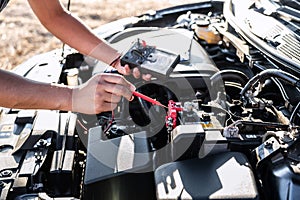 Mechanic repairman checking engine automotive in auto repair service and using digital multimeter testing battery to measure