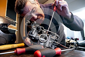 Mechanic repairs a carburetor photo