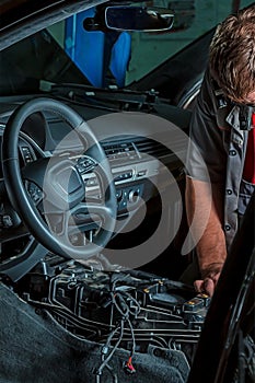 A mechanic repairs a luxury SUV Repair wiring, gearboxes, disassembled interior premium crossover. Removed chairs. Leather