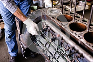 Mechanic repairs old motor of truck in a car repair station. Disassemble engine block vehicle. Motor capital repair. Car service