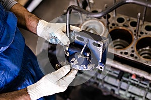 Mechanic repairs old motor of truck in a car repair station. Disassemble engine block vehicle. Motor capital repair. Car service