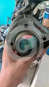 A mechanic\'s hand is holding a motorcycle cylinder piston block head due to improper maintenance
