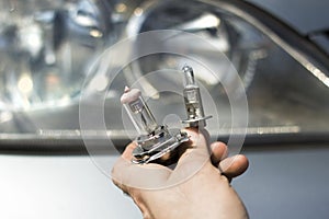 The mechanic`s hands hold the H1 and H7 car bulbs