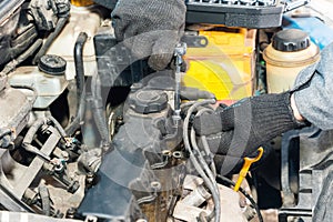 Mechanic\'s hands unscrew the valve cover of an internal combustion engine to replace the gasket
