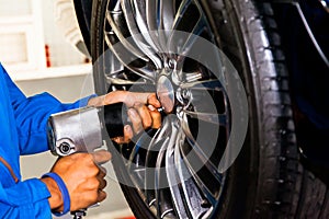 Mechanic screwing or unscrewing car wheel at car service garage