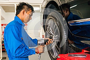 Mechanic screwing or unscrewing car wheel at car service garage