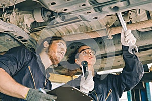 Mechanic service team working check under car suspension on hoist maintenance in garage