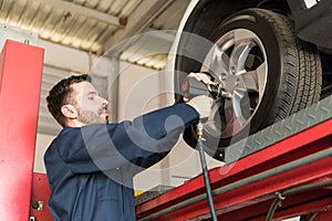 Mechanic Servicing Car Tire With Impact Gun In Garage