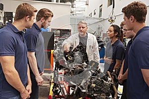 Mechanic showing parts of an engine to apprentices, close up