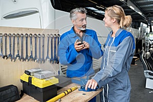 mechanic showing tool to female colleague