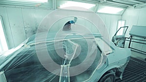 Mechanic spray painting a car in a body shop