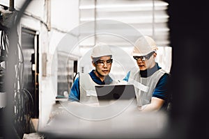 Mechanic and staff engineer talking nearby a machine in a big factory